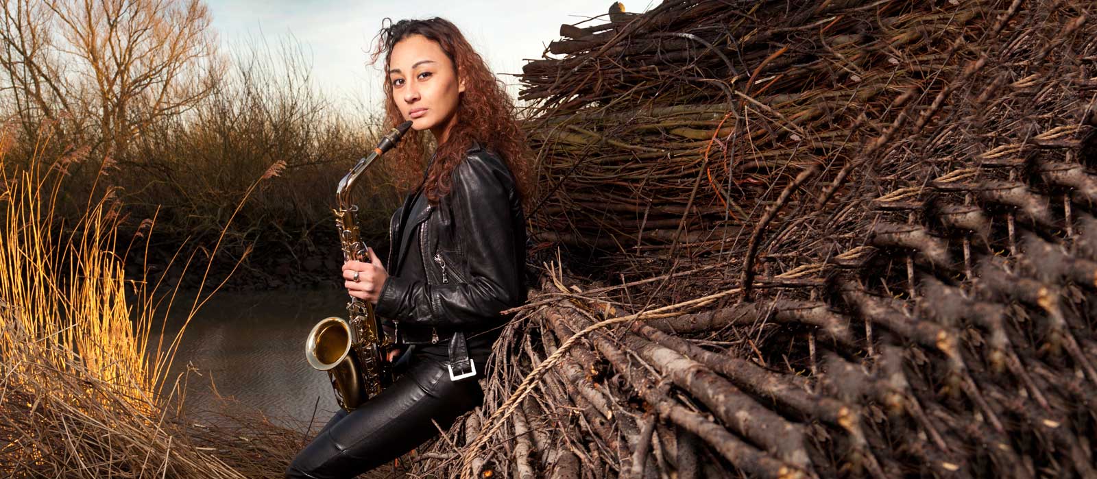 Een vrouw zit buiten bij houten balken en riet