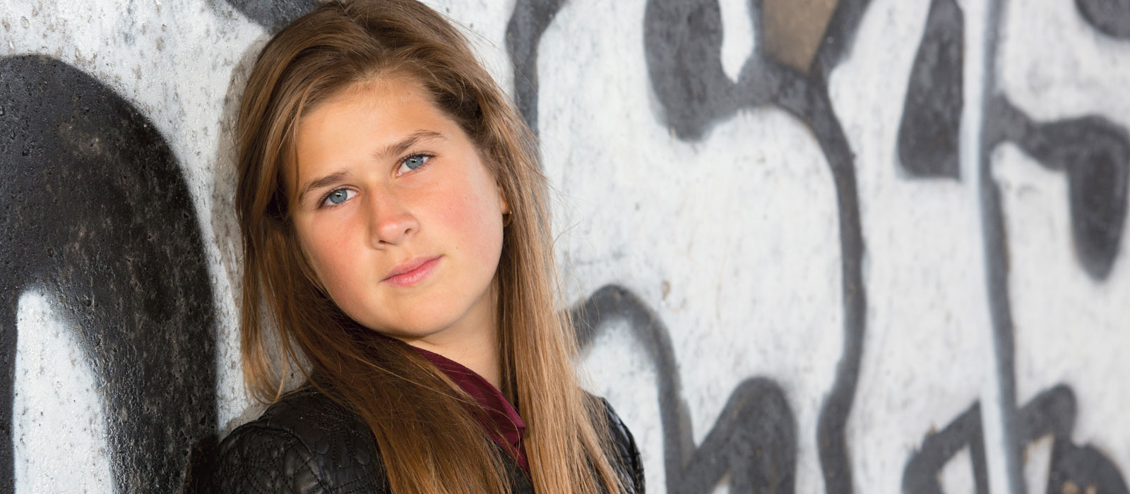 Portret van een jonge vrouw voor een muur met graffiti